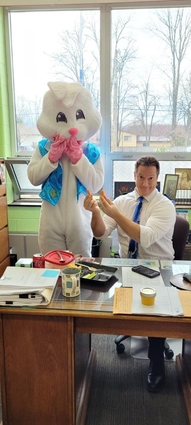 A man in a bunny costume is holding a carrot.