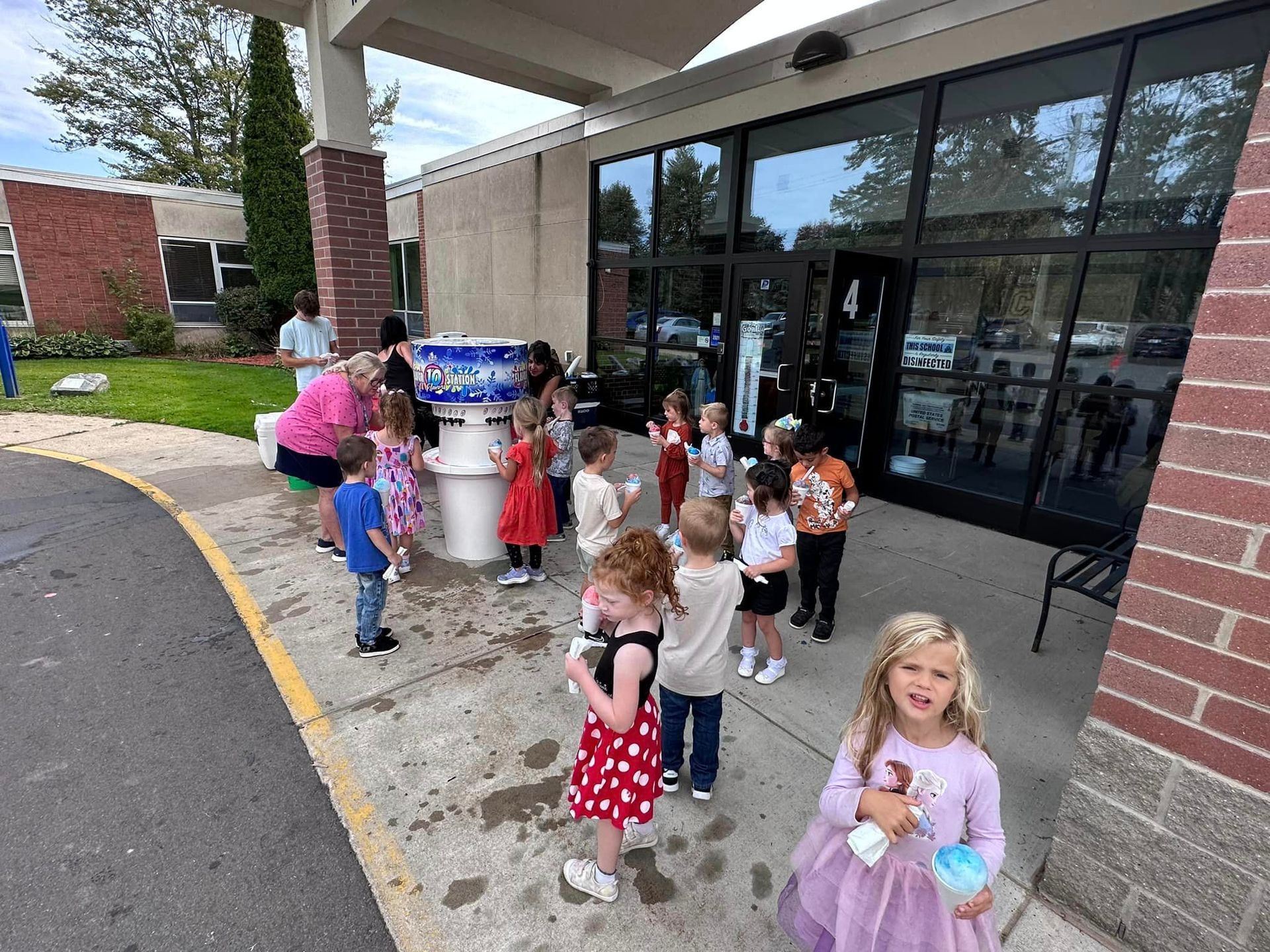 A group of kids and an adult chaperone all get snow cones.