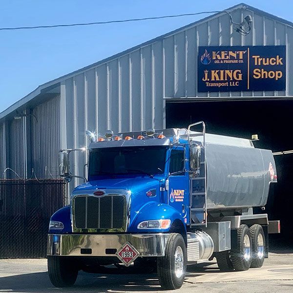 Blue tanker truck parked outside Kent Truck Shop building