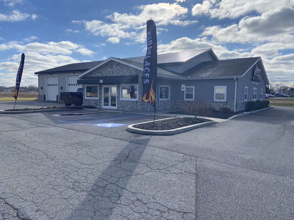 Gray building with a garage, blue sky, and promotional flags on a paved lot.