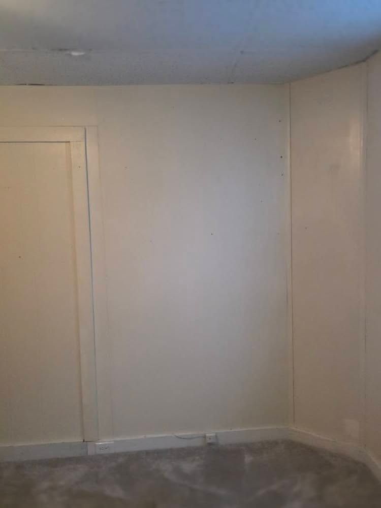 Empty beige room with white trim and a gray carpeted floor