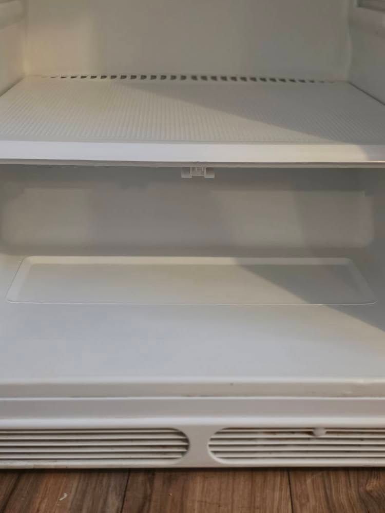 Empty white refrigerator interior with shelves and a vent at the bottom