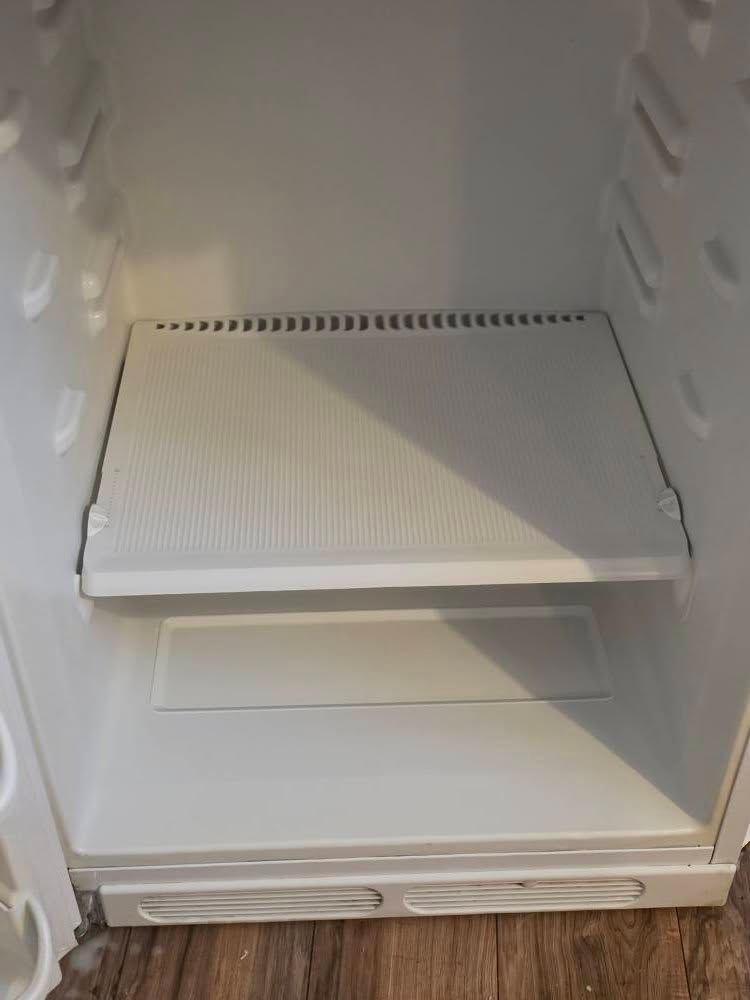 Empty white refrigerator interior with shelves and a bottom drawer