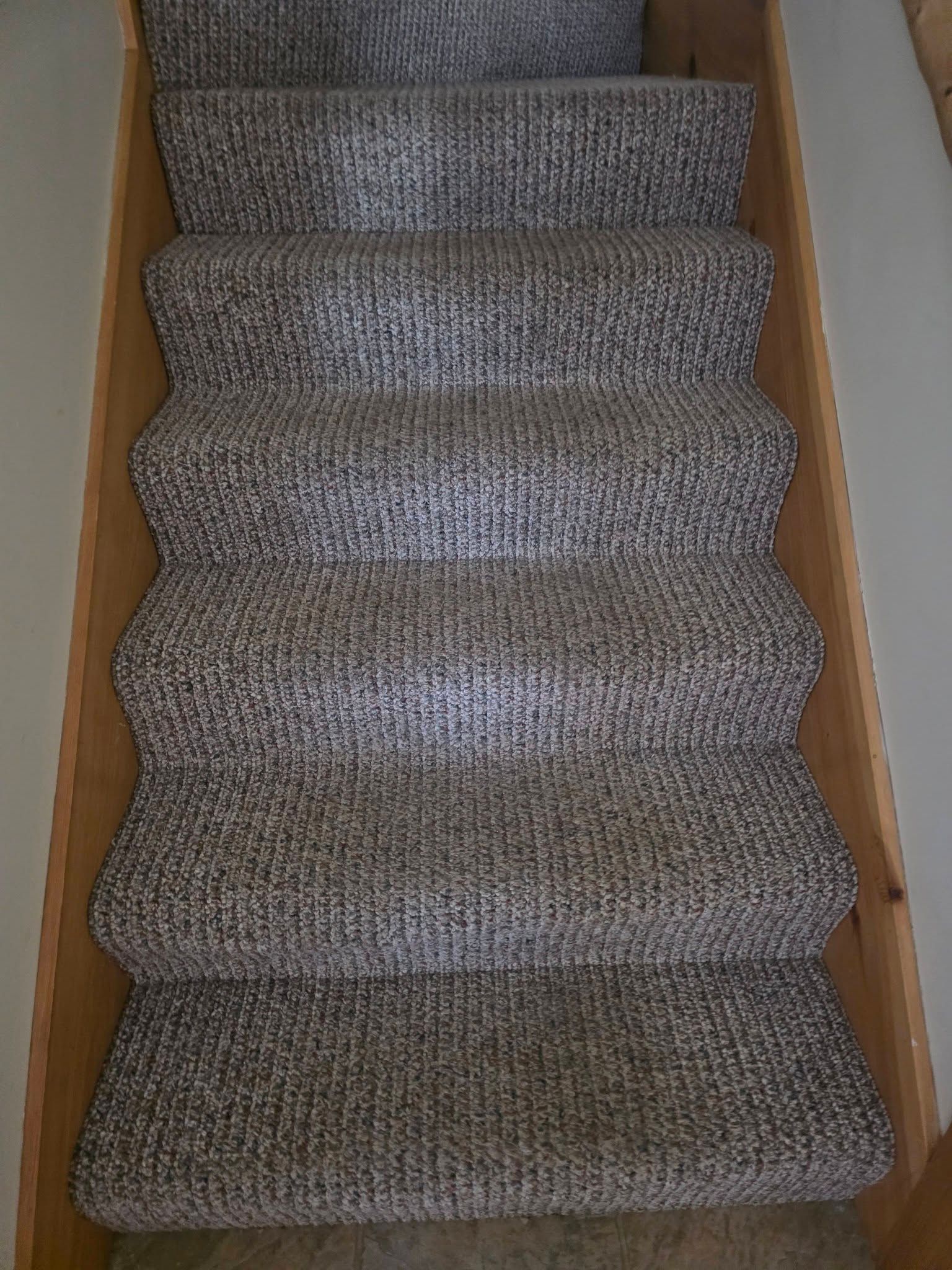 Carpeted staircase with beige wooden sides, viewed from above