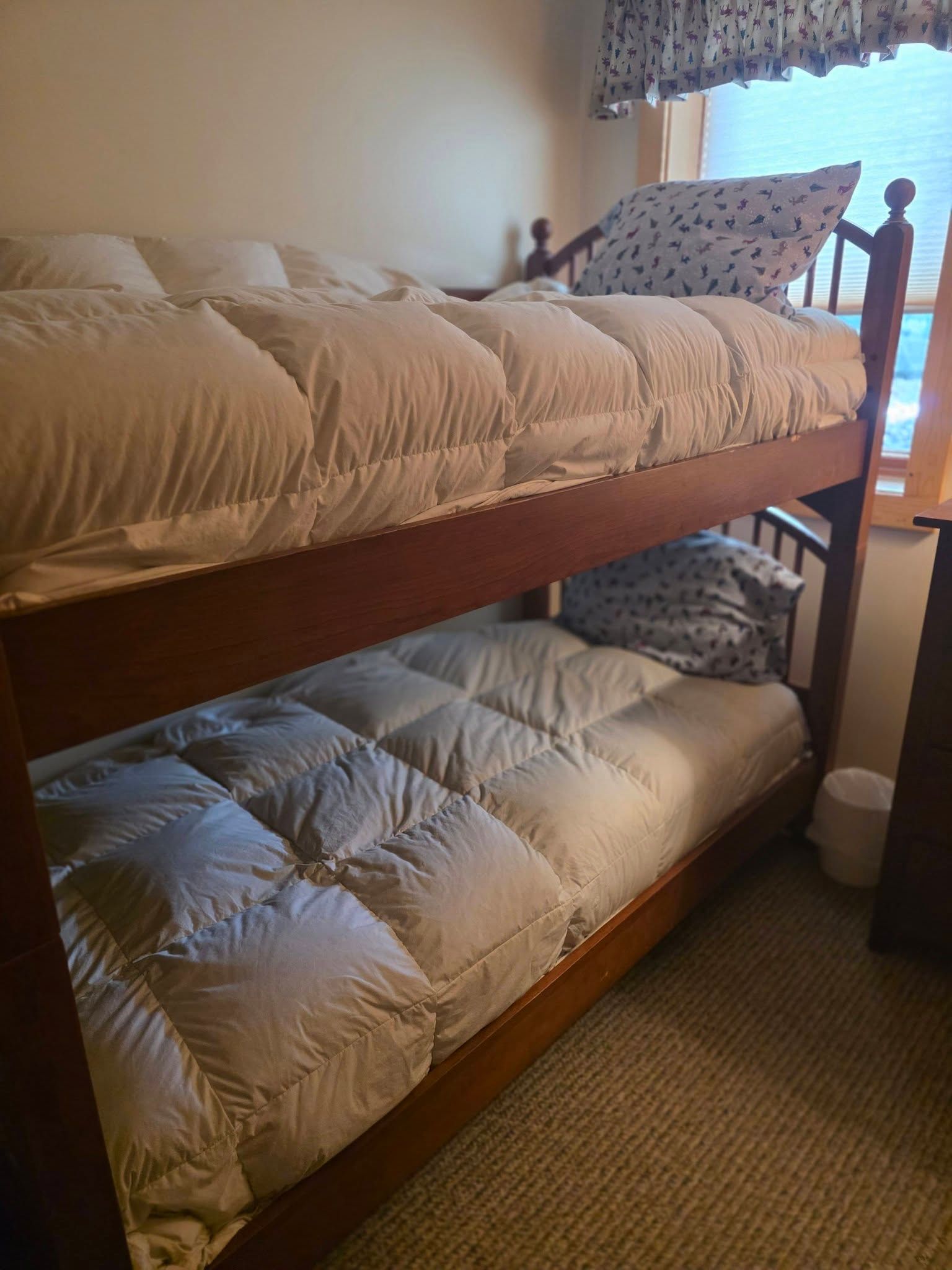 Bunk bed with beige top bedding and gray bottom bedding in a small room.