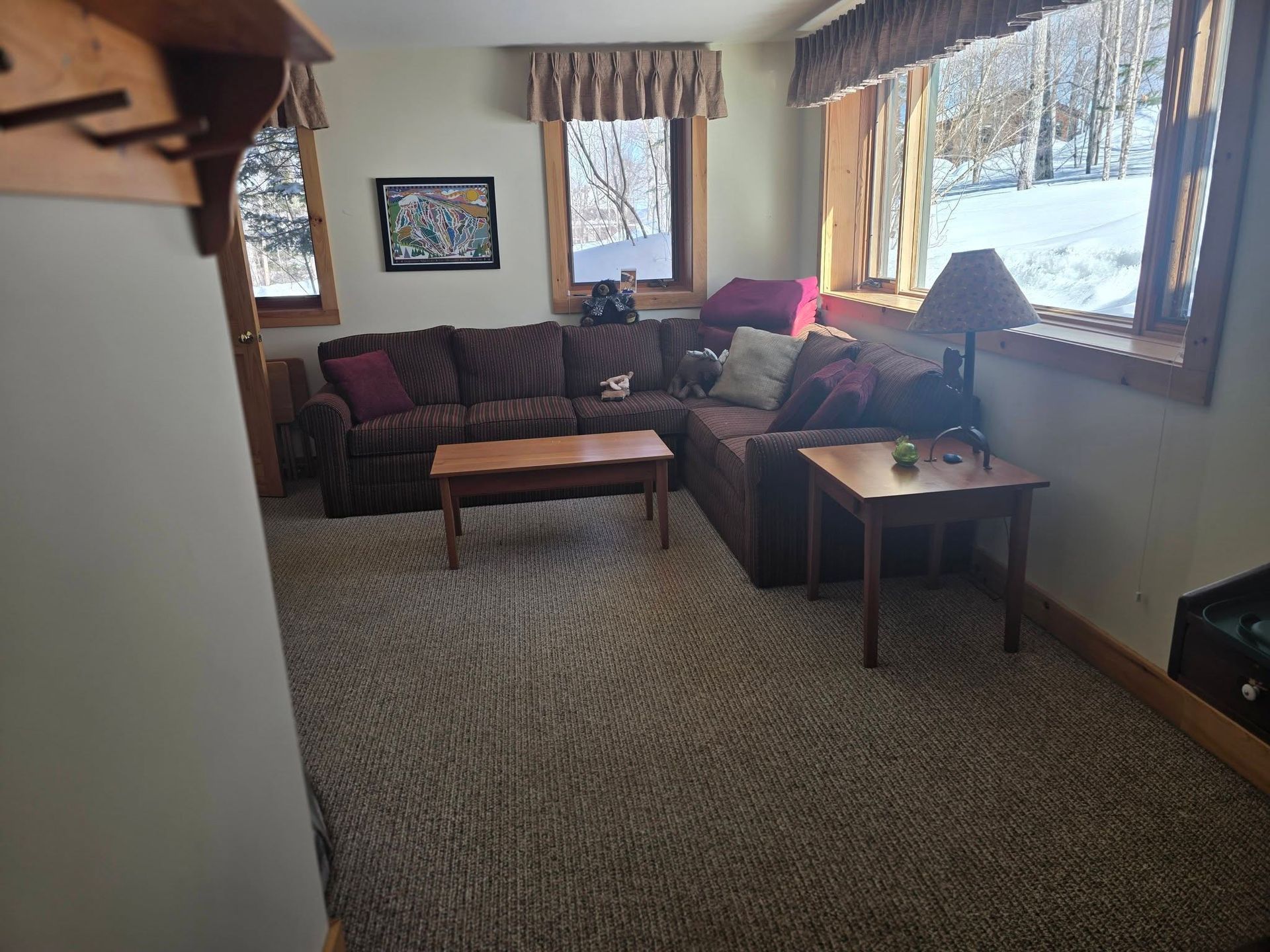 Cozy living room with sectional sofa, coffee table, lamp, and large windows with snowy view
