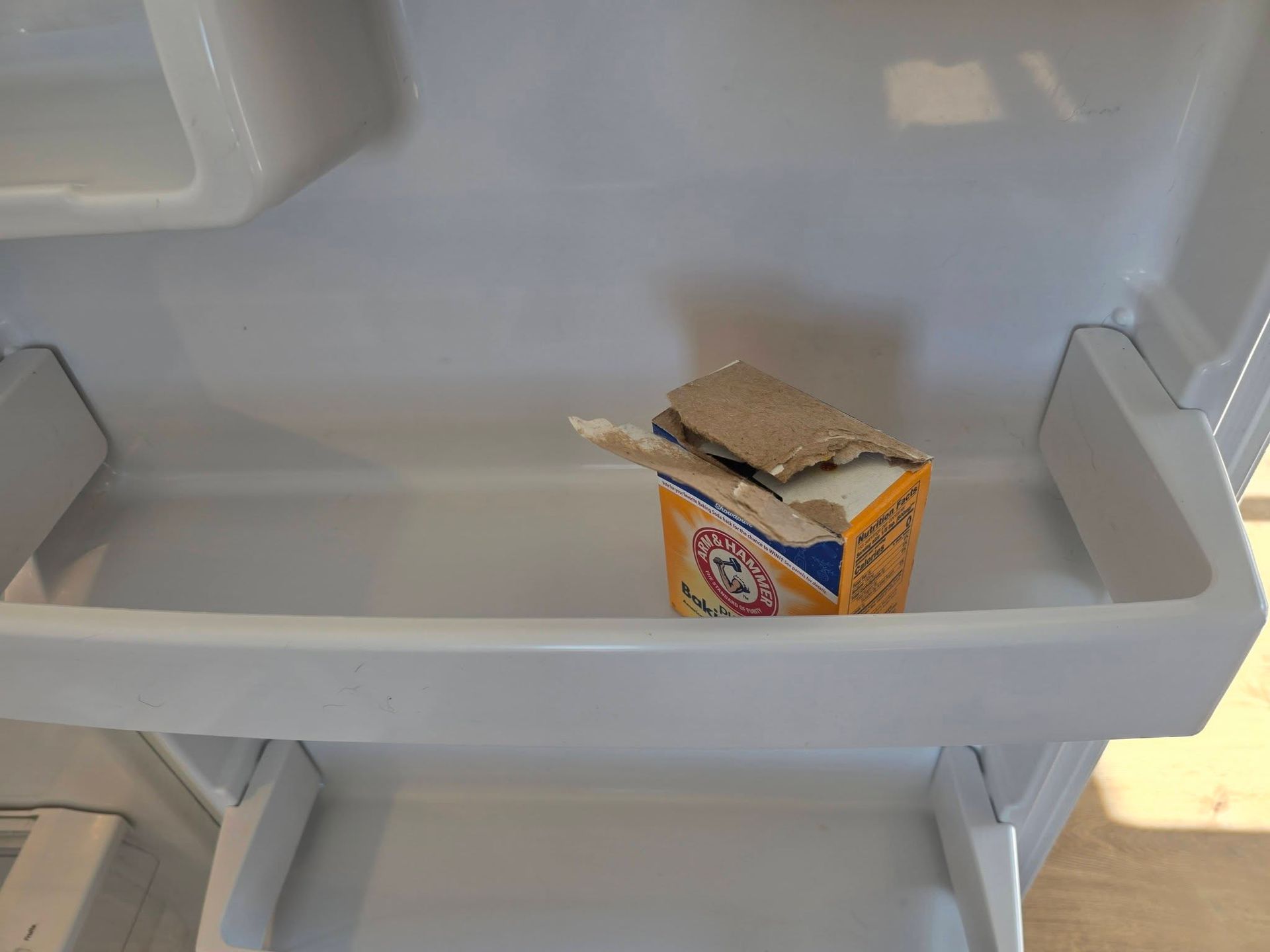 Small orange carton with a torn top inside a gray refrigerator shelf
