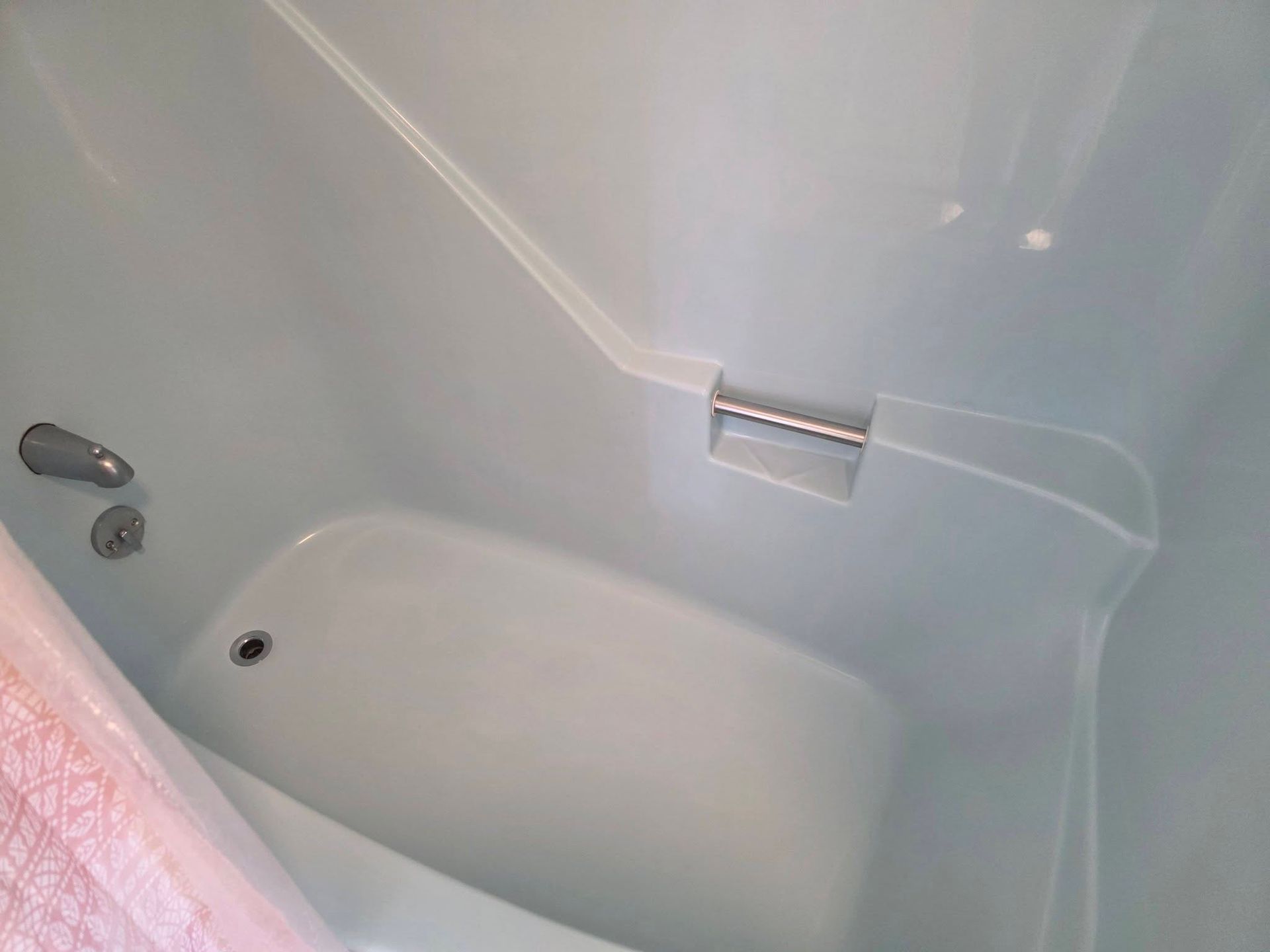 White bathtub with built-in seat and faucet in a bathroom corner