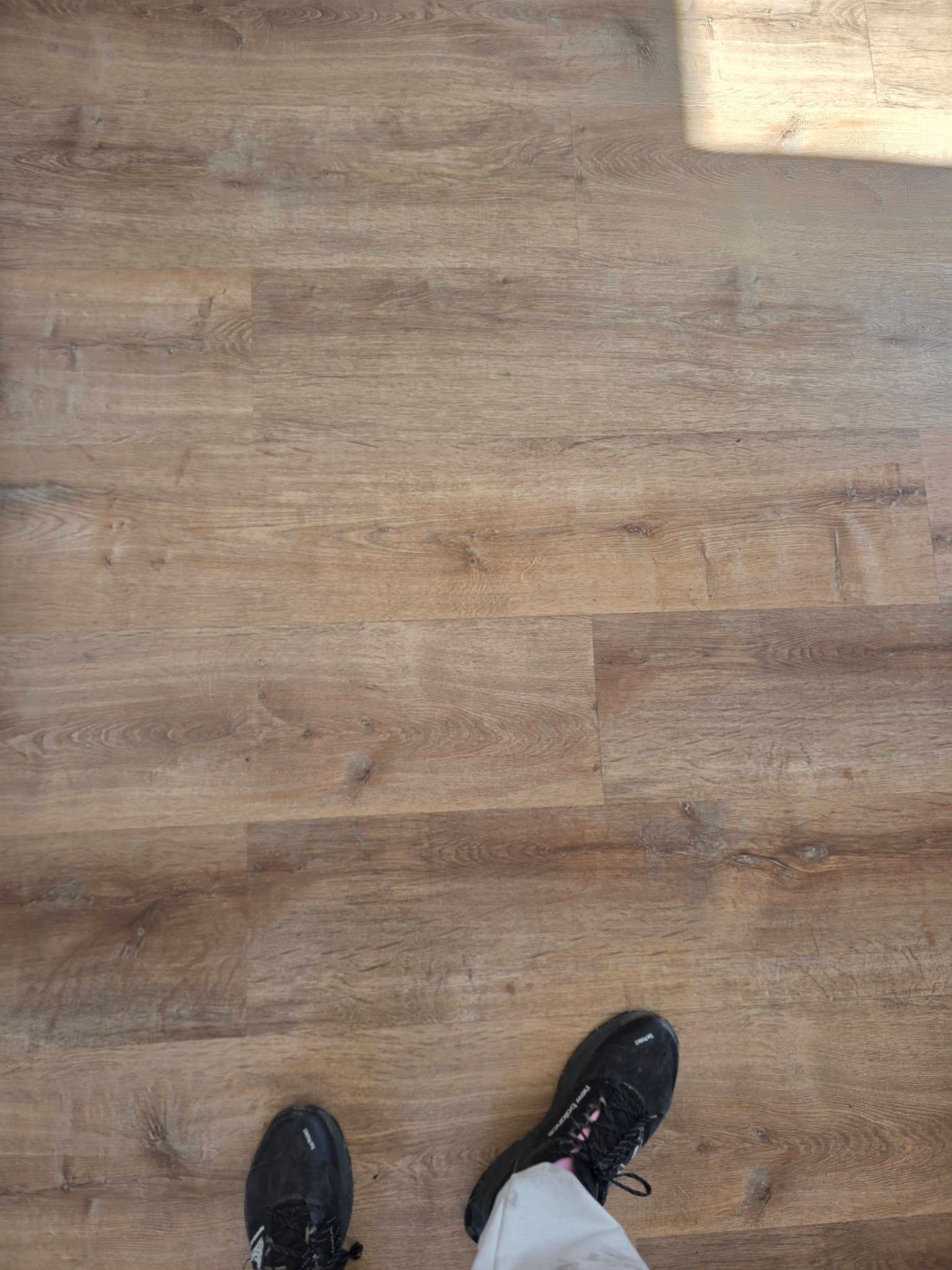 Wood-look floor with the tips of two black shoes visible at the bottom.