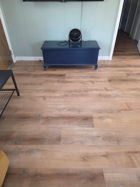 Empty room with wood flooring, built-in alcove, and a blue cabinet topped by a small black fan.