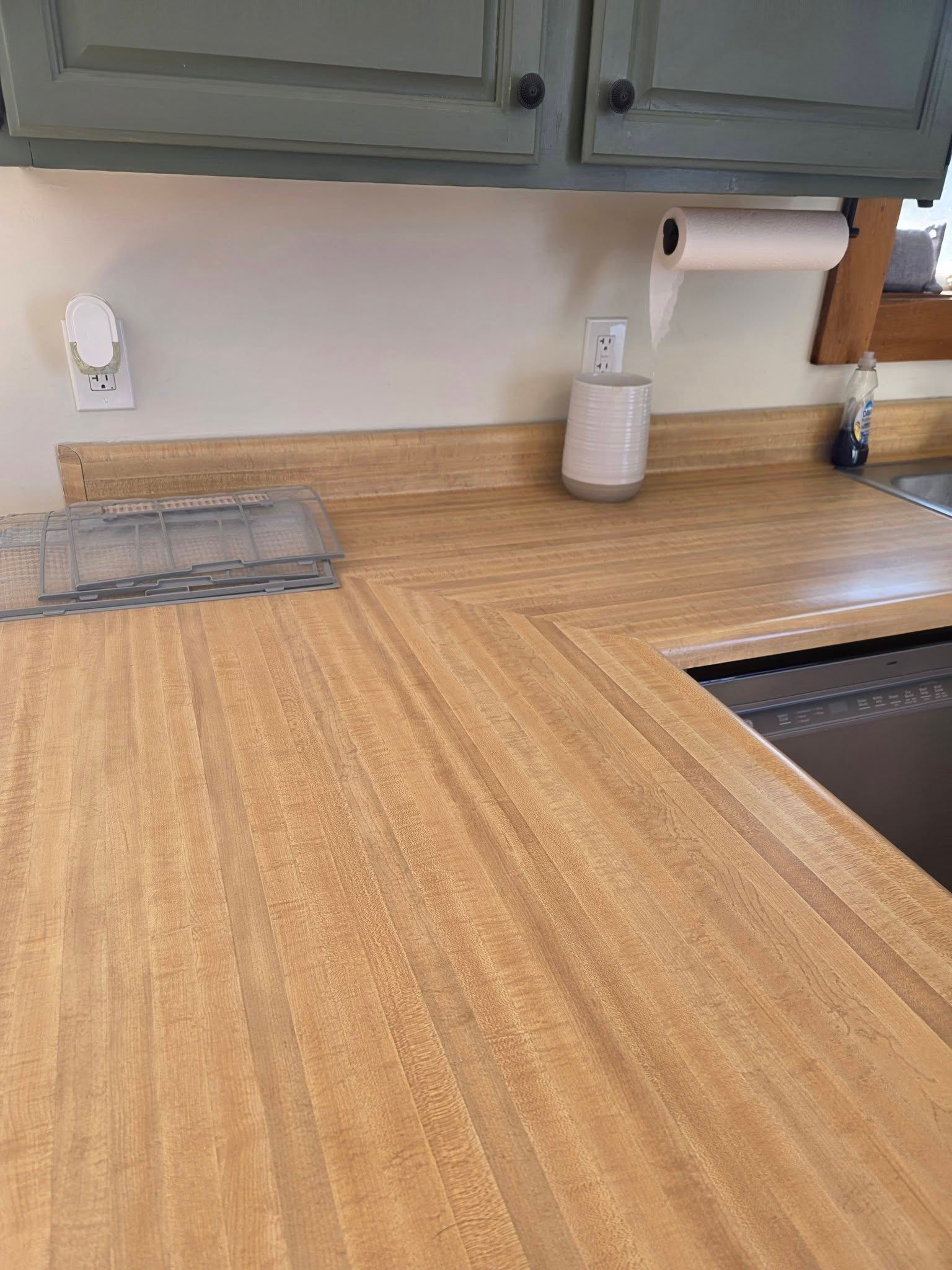 Empty kitchen countertop with wood-grain surface, sink on the right, and gray cabinets above
