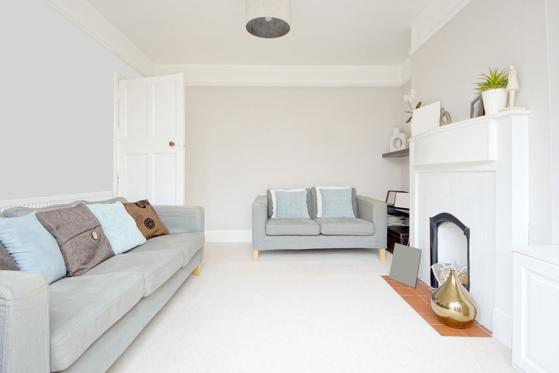 Bright living room with white sofa, gray loveseat, and white fireplace with plants and decor