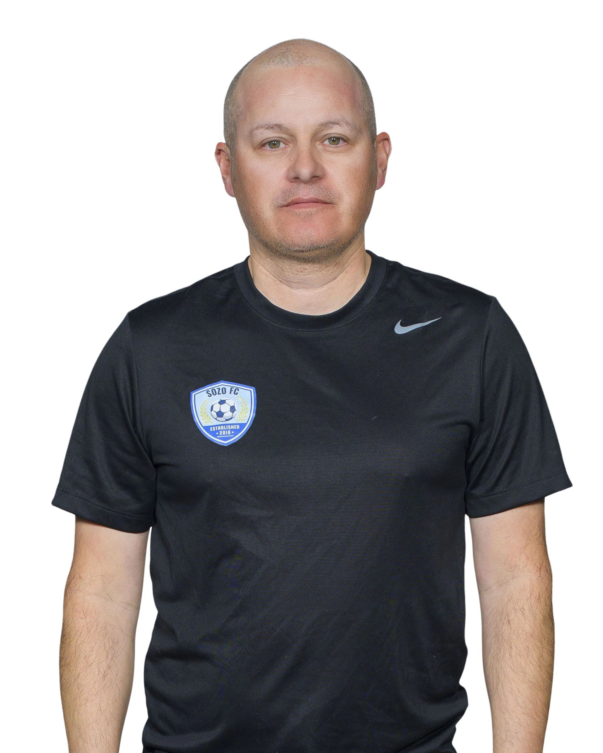 A man wearing a black hat and a black shirt is smiling.