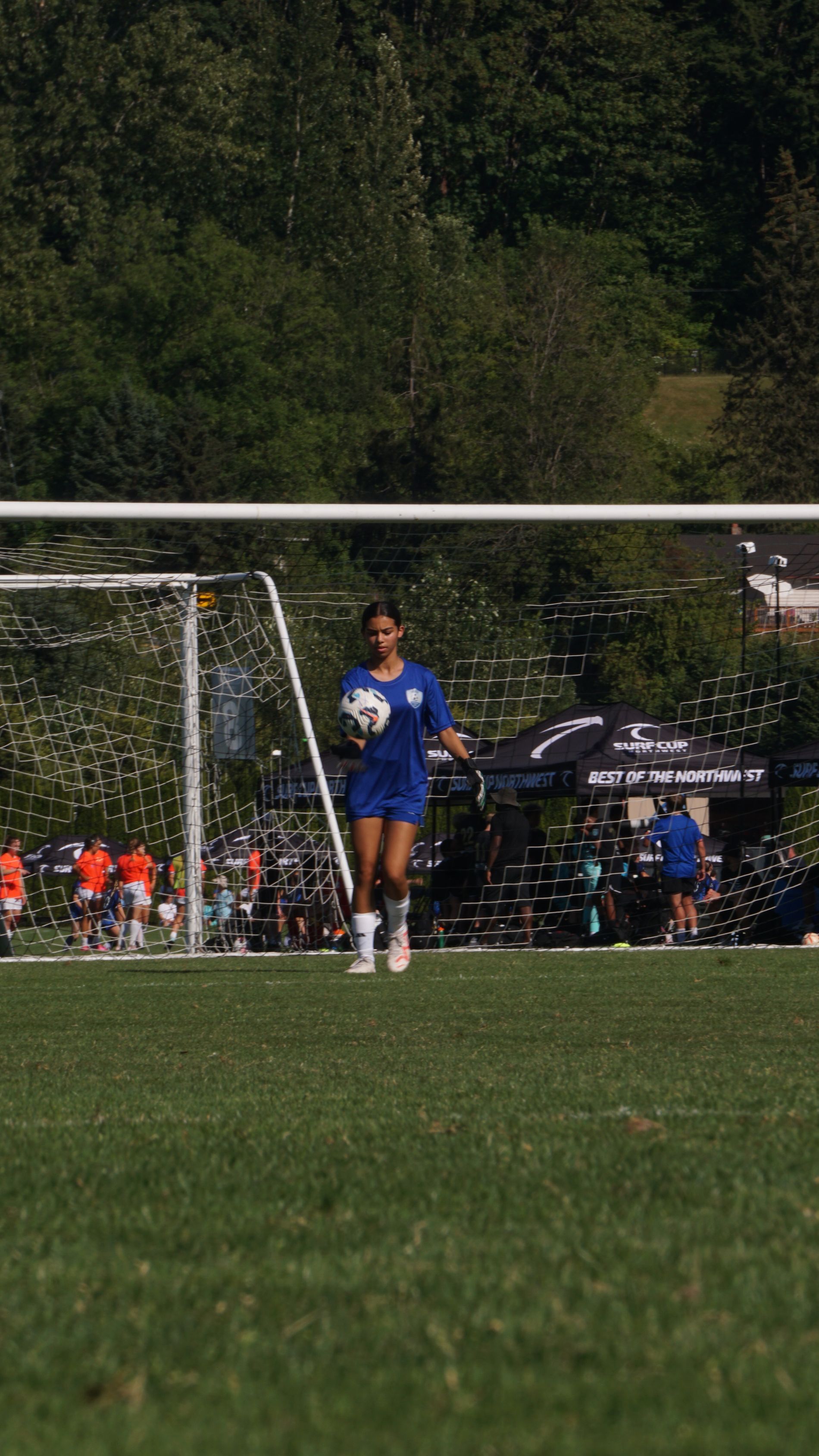 A woman is holding a soccer ball on a field.