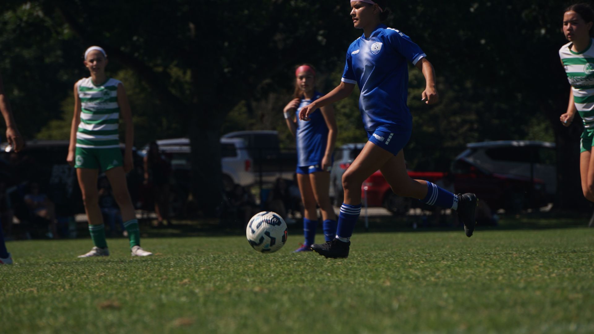 A group of young girls are playing soccer on a field.