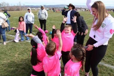 A group of children wearing pink shirts are playing on a field.