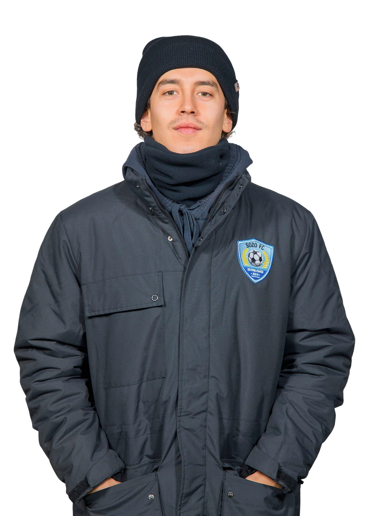 Person in a black winter coat, knit hat, and scarf, standing against a white background.