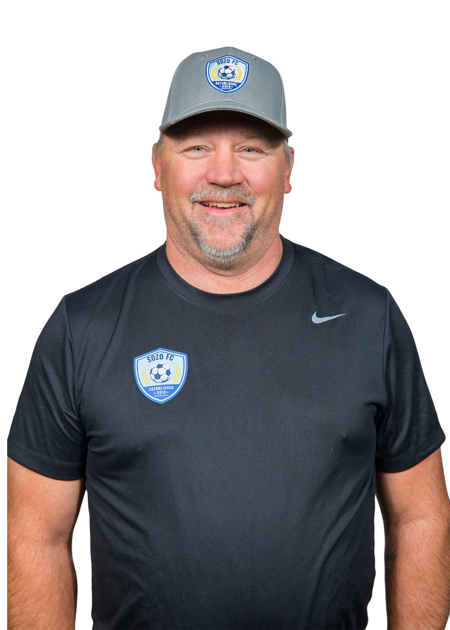 A man wearing a hat and a gray shirt is standing in a field.