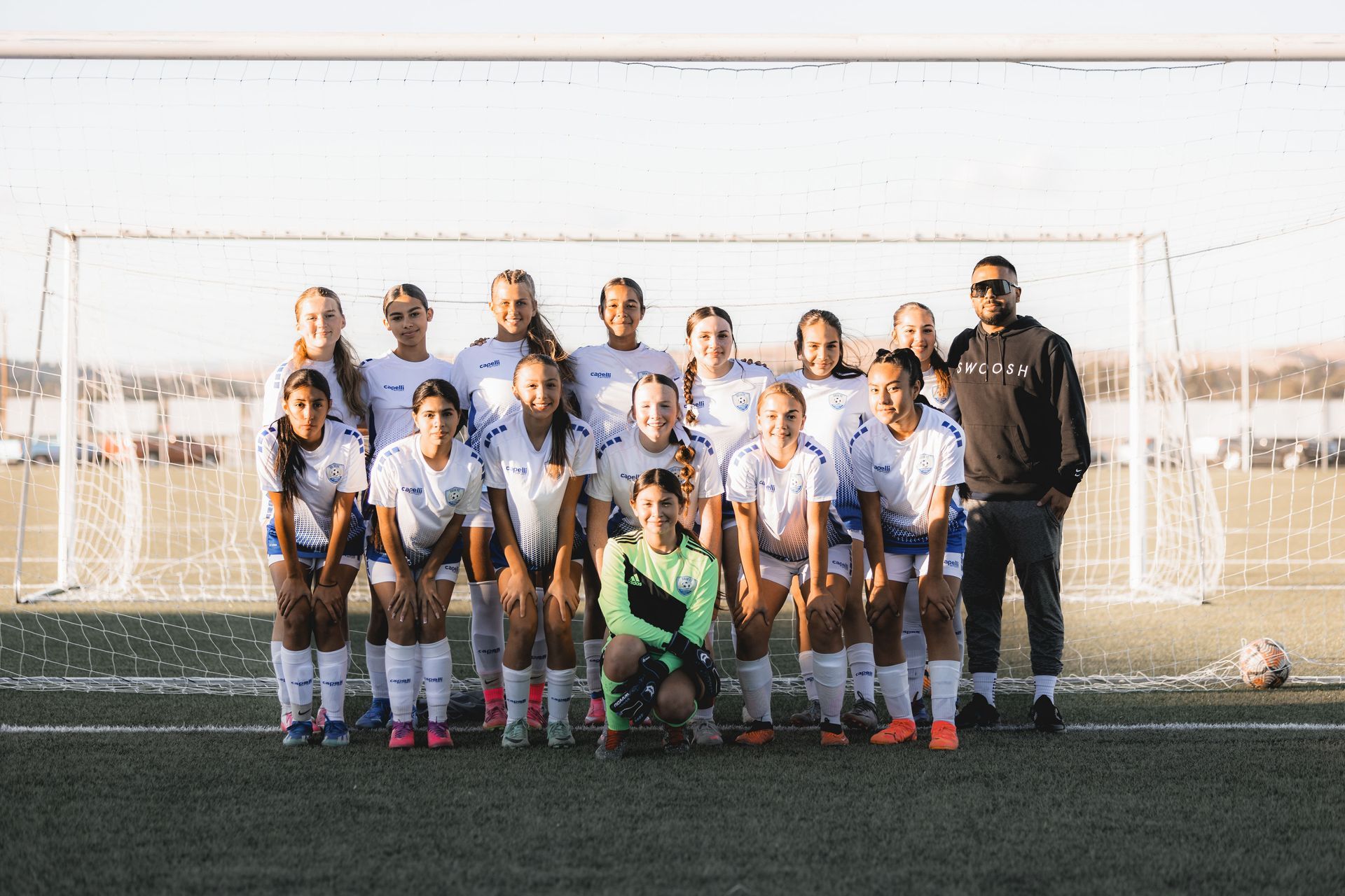 A soccer team is posing for a picture on a field.