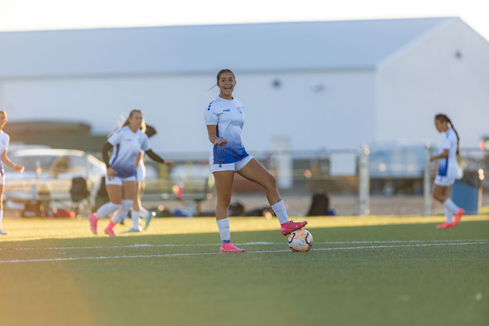 A woman is kicking a soccer ball on a field.