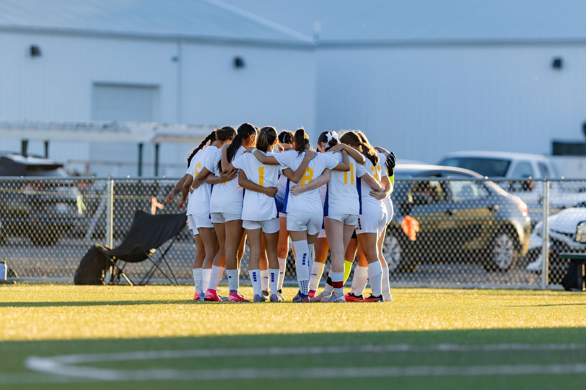 A group of female soccer players are huddled together on a field.