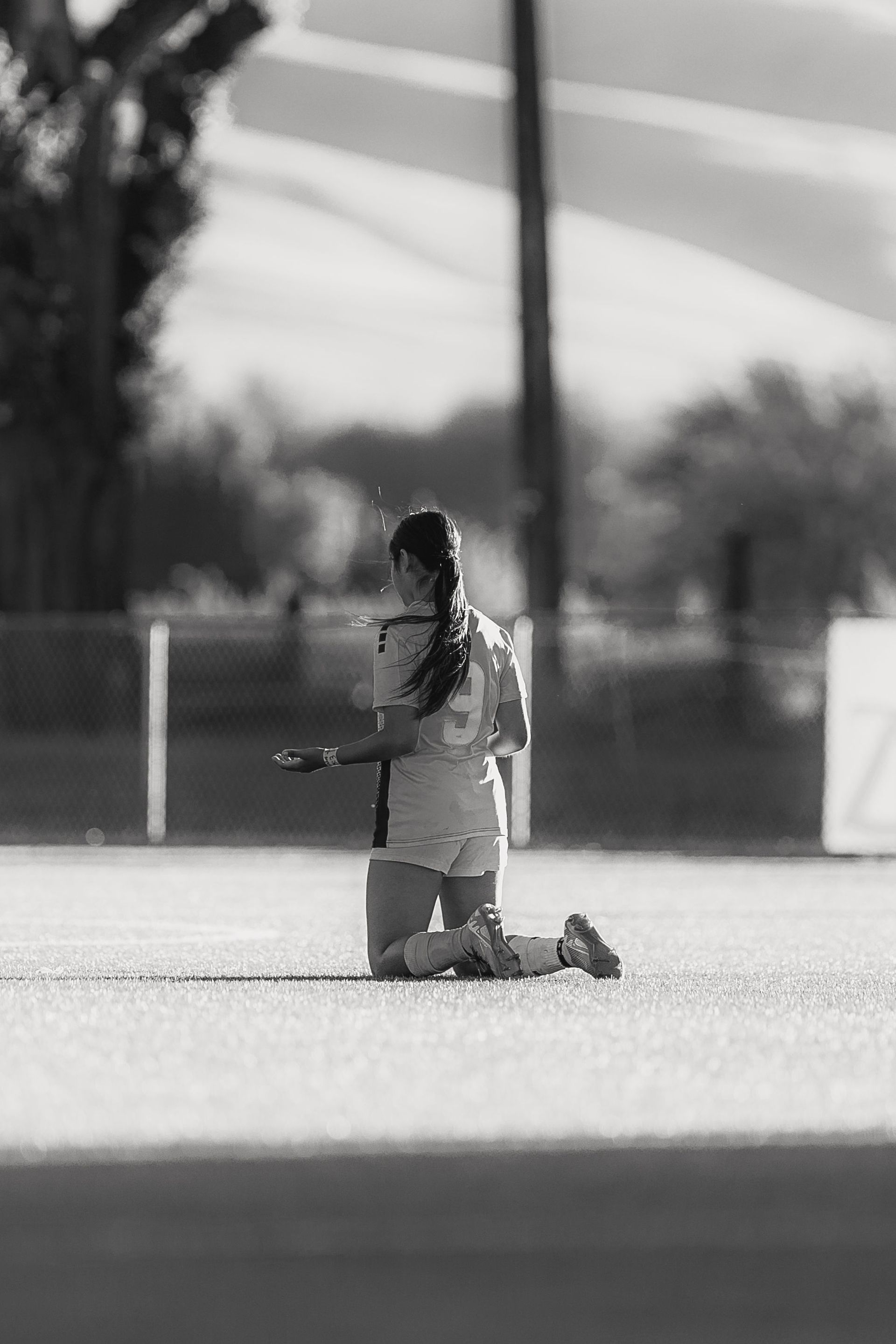 A black and white photo of a soccer player kneeling on the field.