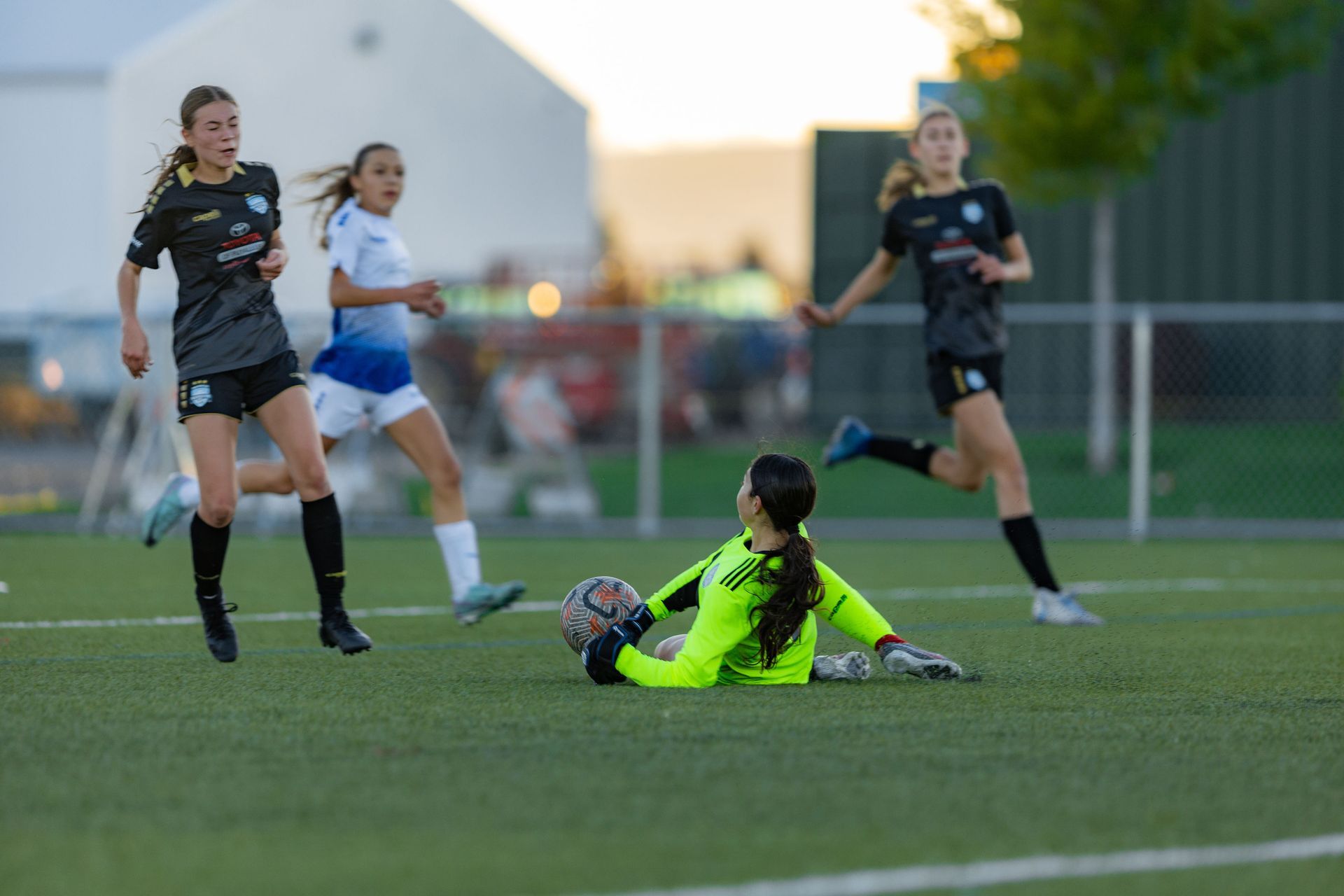 A group of female soccer players are playing a game on a field.