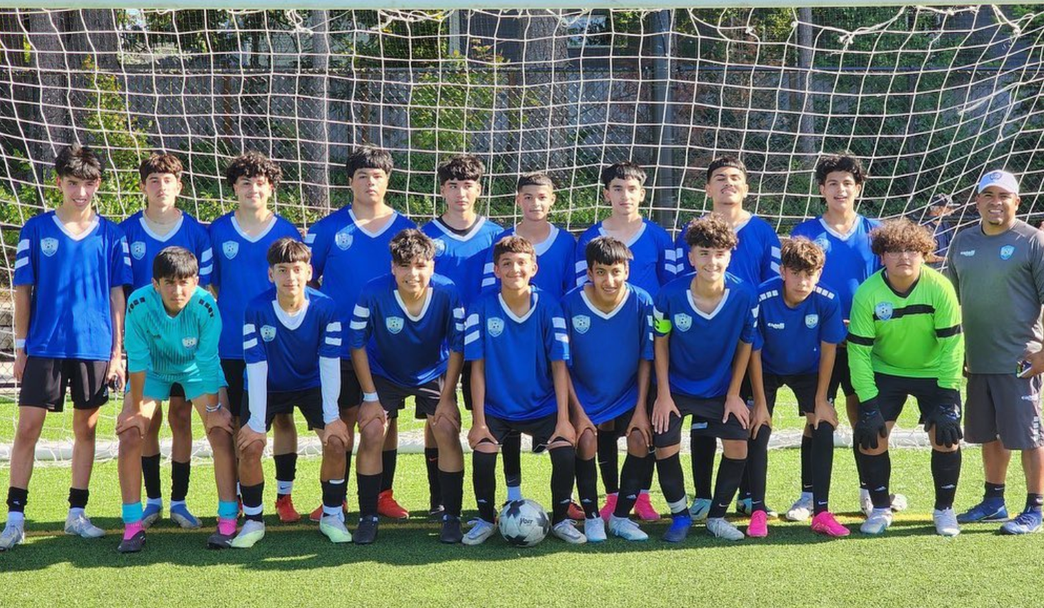 A group of young boys are posing for a picture on a soccer field.