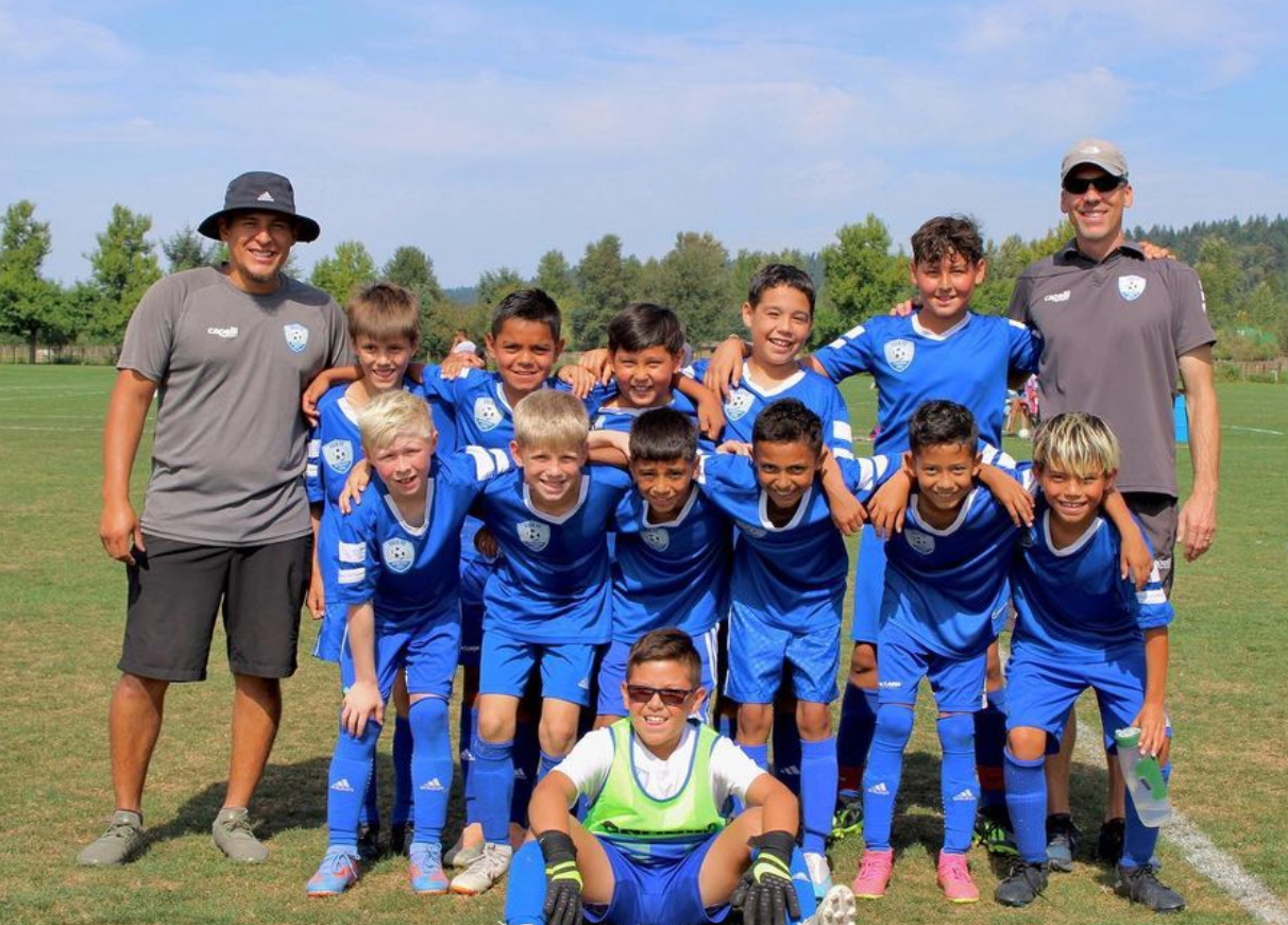 A group of young boys are posing for a picture on a soccer field.