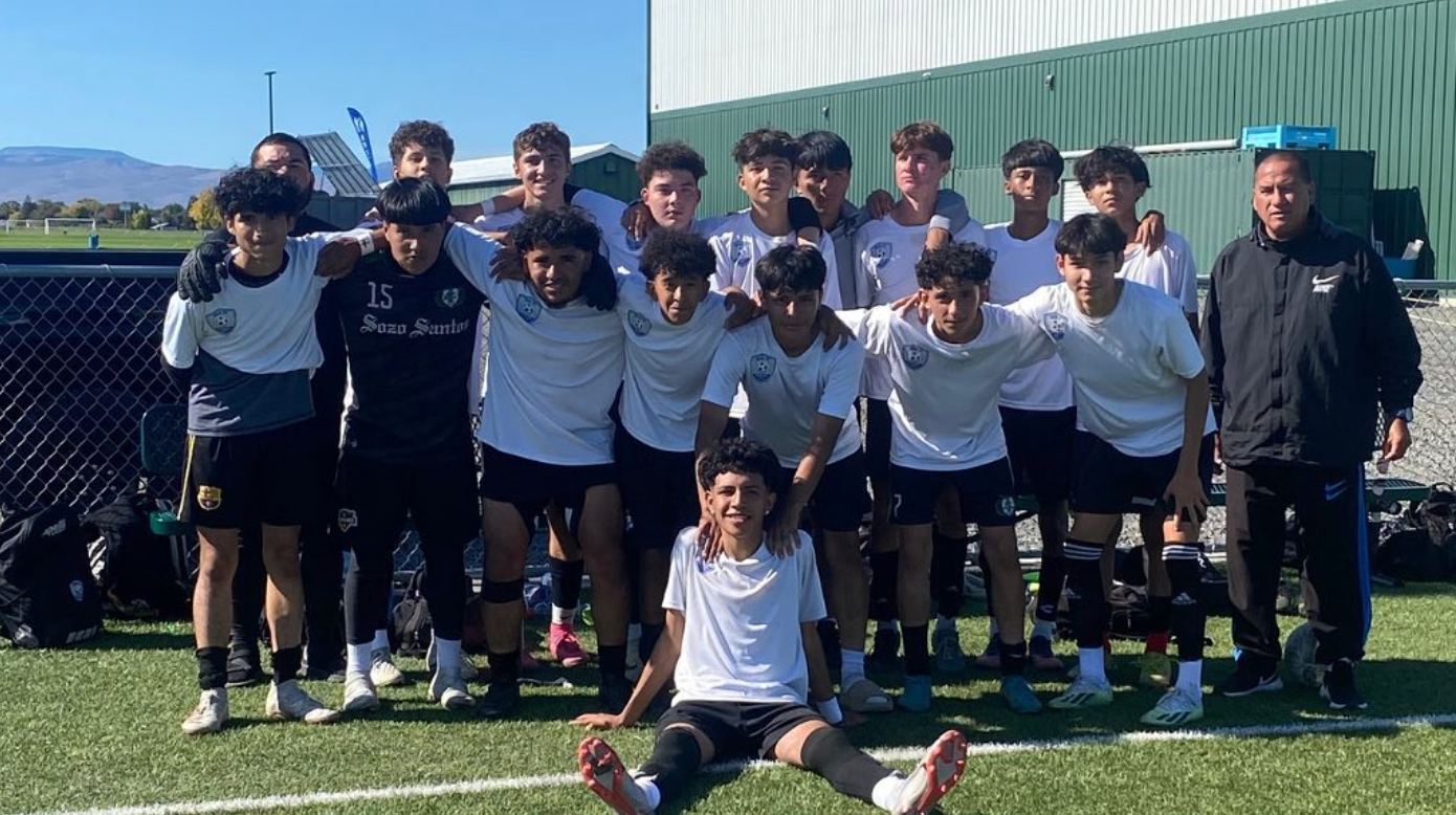 A group of young men are posing for a picture on a soccer field.