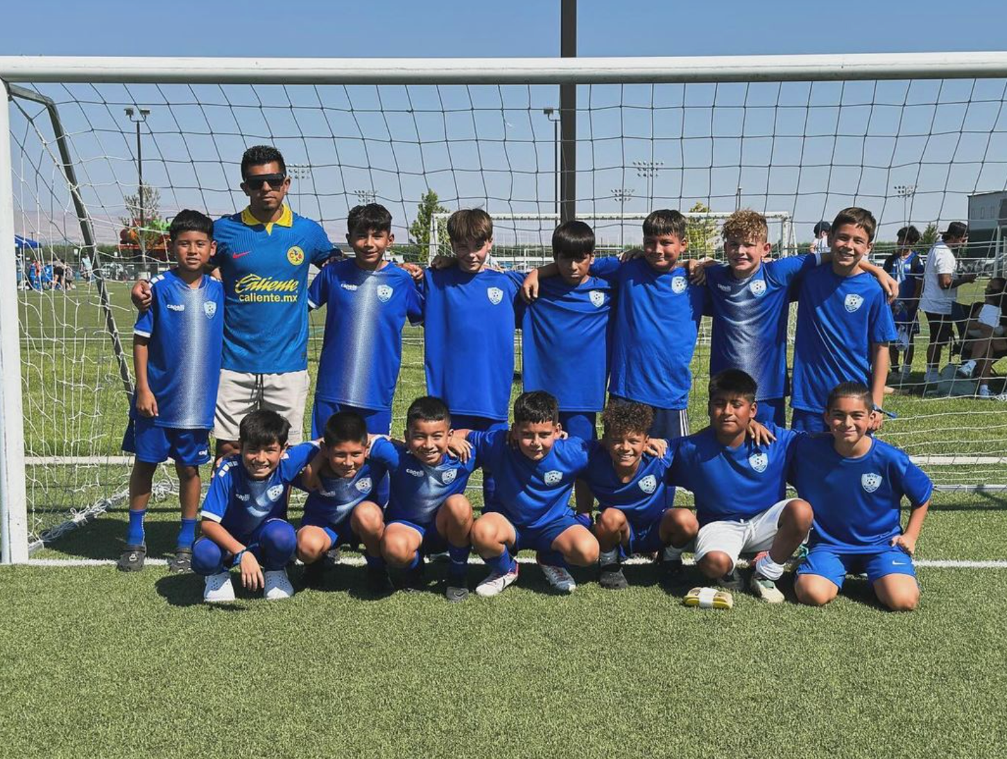 A group of young boys are posing for a picture on a soccer field.