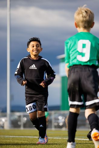 Two young boys are playing soccer on a field.
