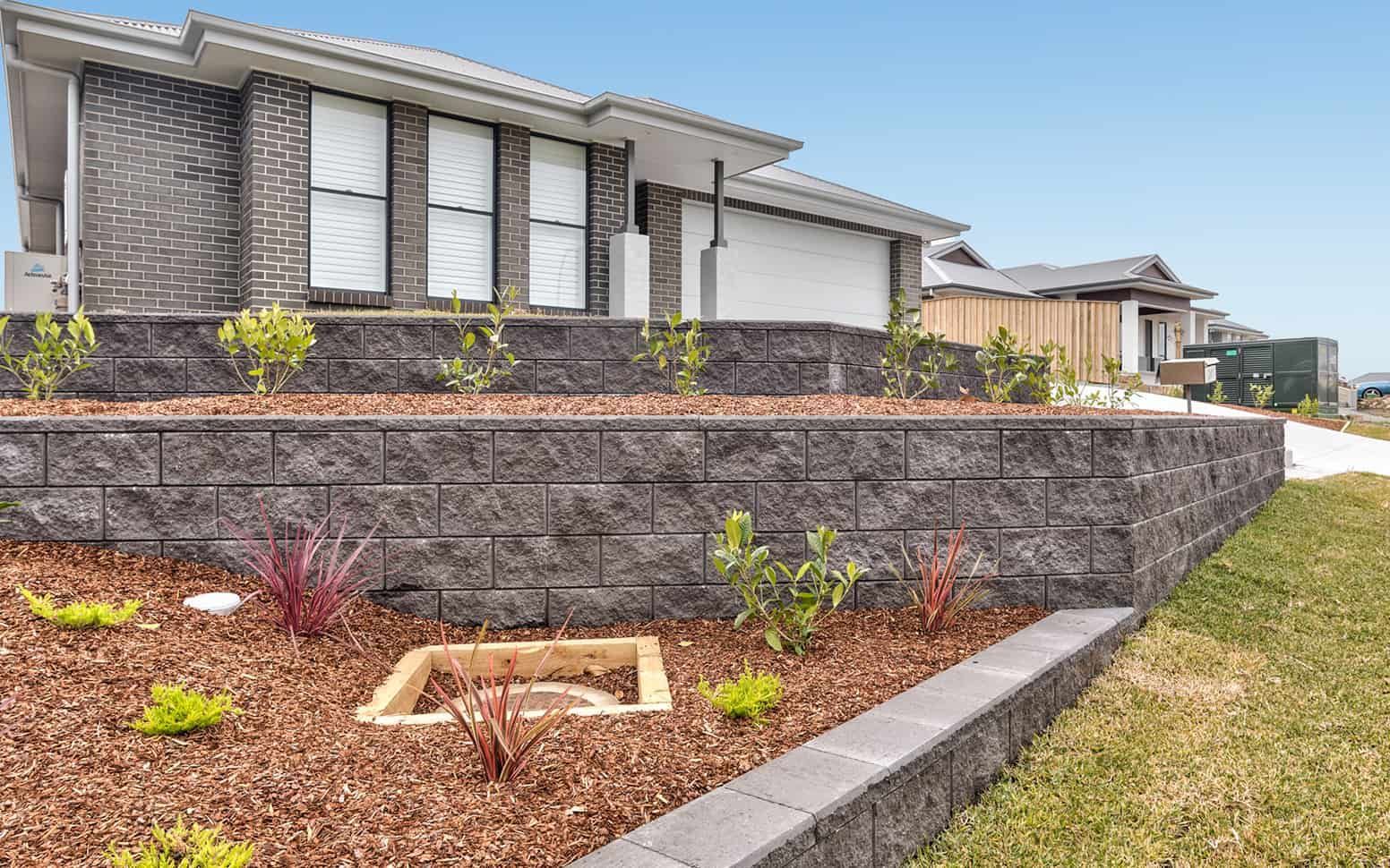 A potted plant is sitting in front of a white brick wall — Premier Bricks, Blocks & Pavers In Heatherbrae, NSW