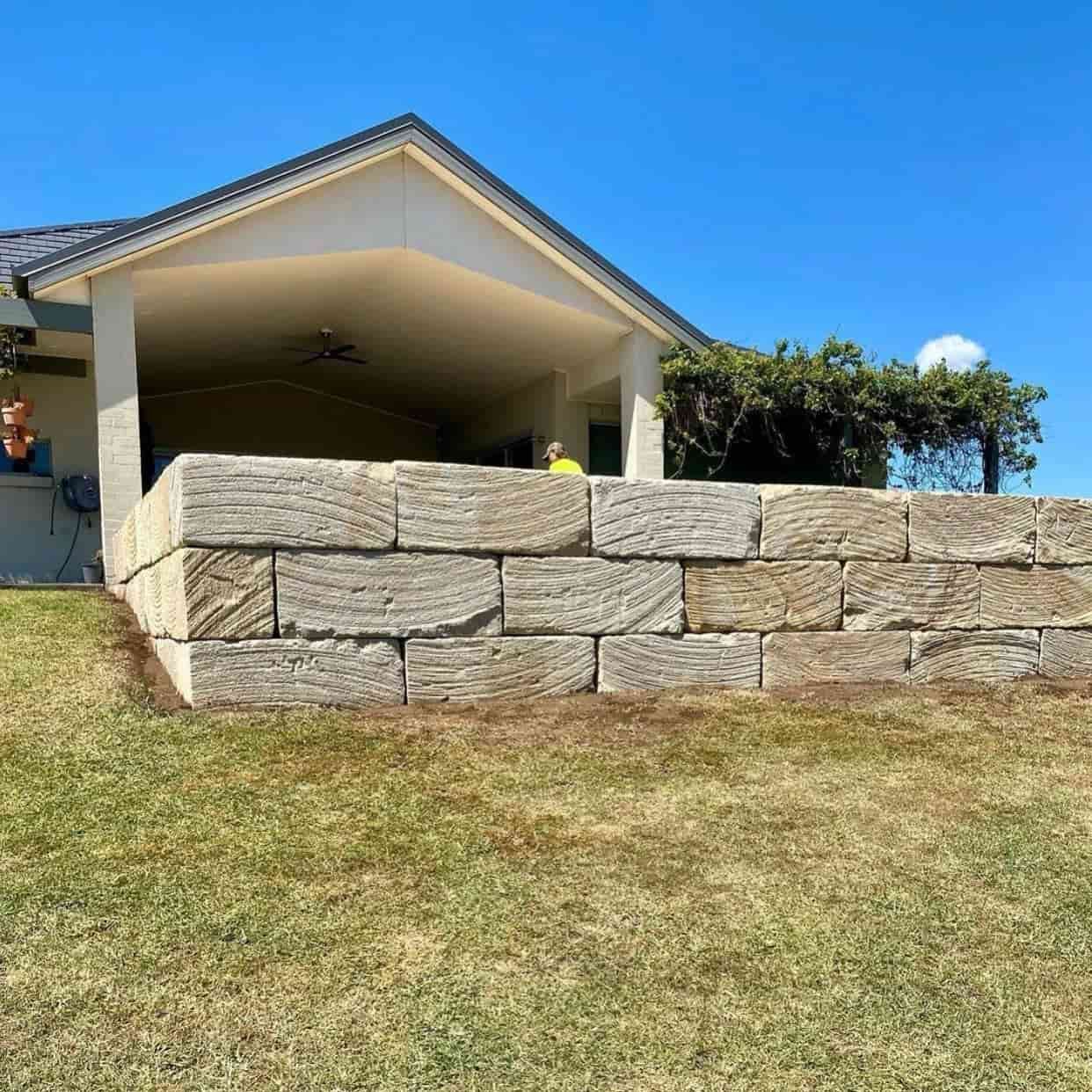 There is a large stone wall in front of a house — Premier Bricks, Blocks & Pavers In Heatherbrae, NSW