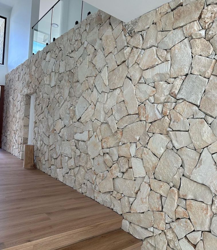 A Stone Wall In A Hallway With Wooden Floors — Premier Bricks, Blocks & Pavers In Heatherbrae, NSW