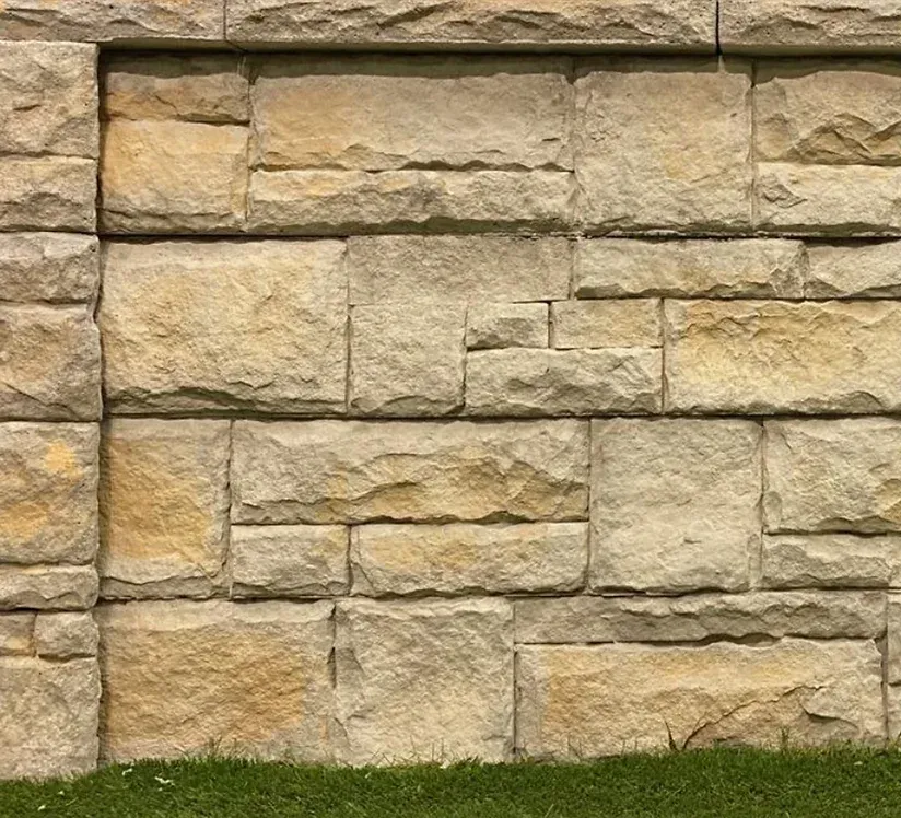 Tan and gray stone wall with grass at the bottom — Premier Bricks, Blocks & Pavers In Heatherbrae, NSW