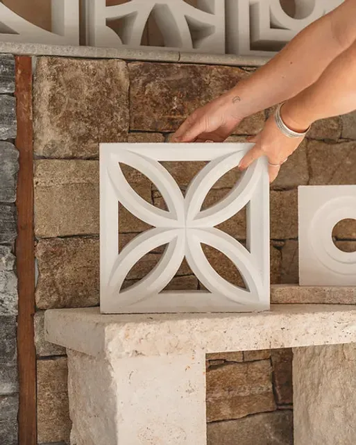 White decorative concrete block with floral pattern against stone wall — Premier Bricks, Blocks & Pavers In Heatherbrae, NSW