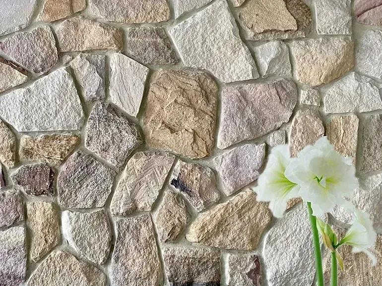Stone wall background with white flowers — Premier Bricks, Blocks & Pavers In Heatherbrae, NSW
