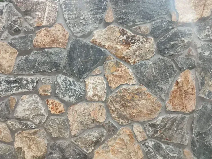Stone wall with gray, brown, and tan rocks set in gray mortar — Premier Bricks, Blocks & Pavers In Heatherbrae, NSW