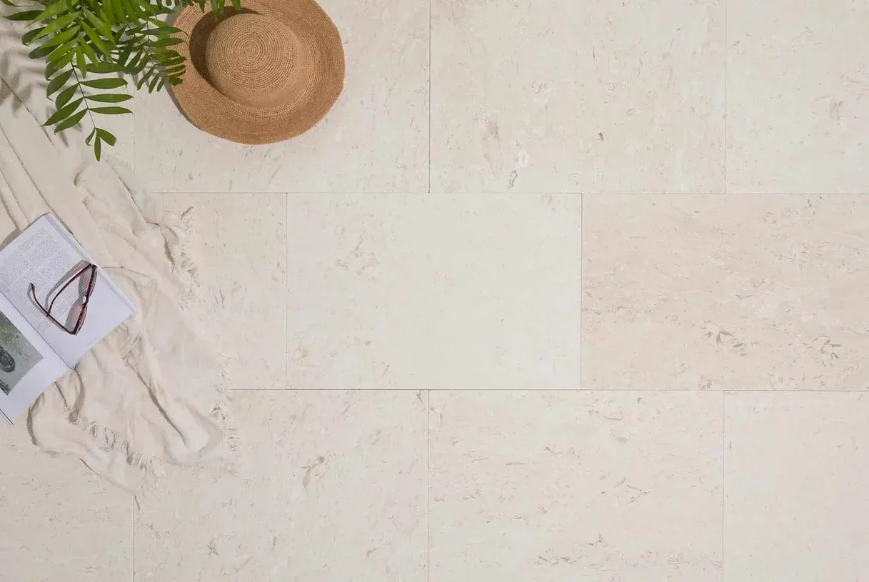 Sun hat, sunglasses, and book on cream-colored stone tile — Premier Bricks, Blocks & Pavers In Heatherbrae, NSW