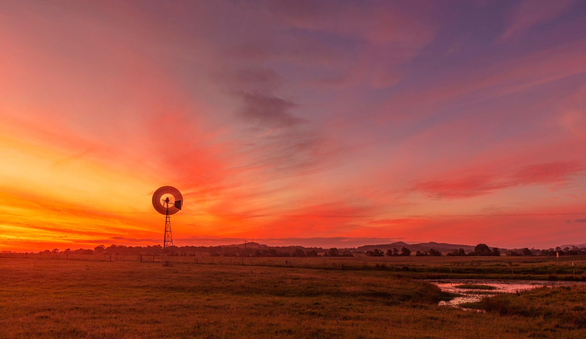 There Is A Windmill In The Middle Of A Field At Sunset — Premier Bricks, Blocks & Pavers In Maitland, NSW