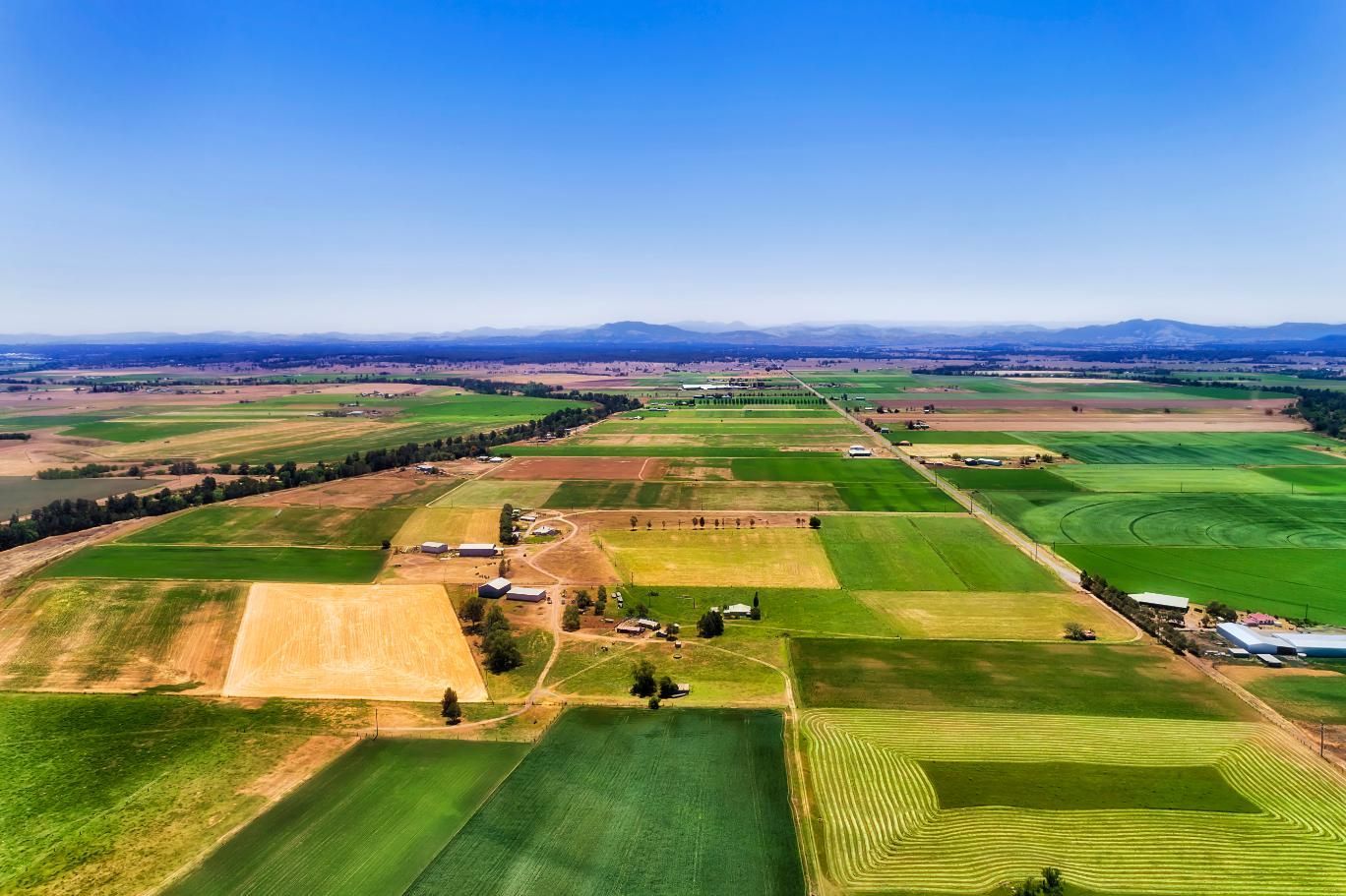 An Aerial View Of A Lush Green Field With Mountains In The Background — Premier Bricks, Blocks & Pavers In Singleton, NSW
