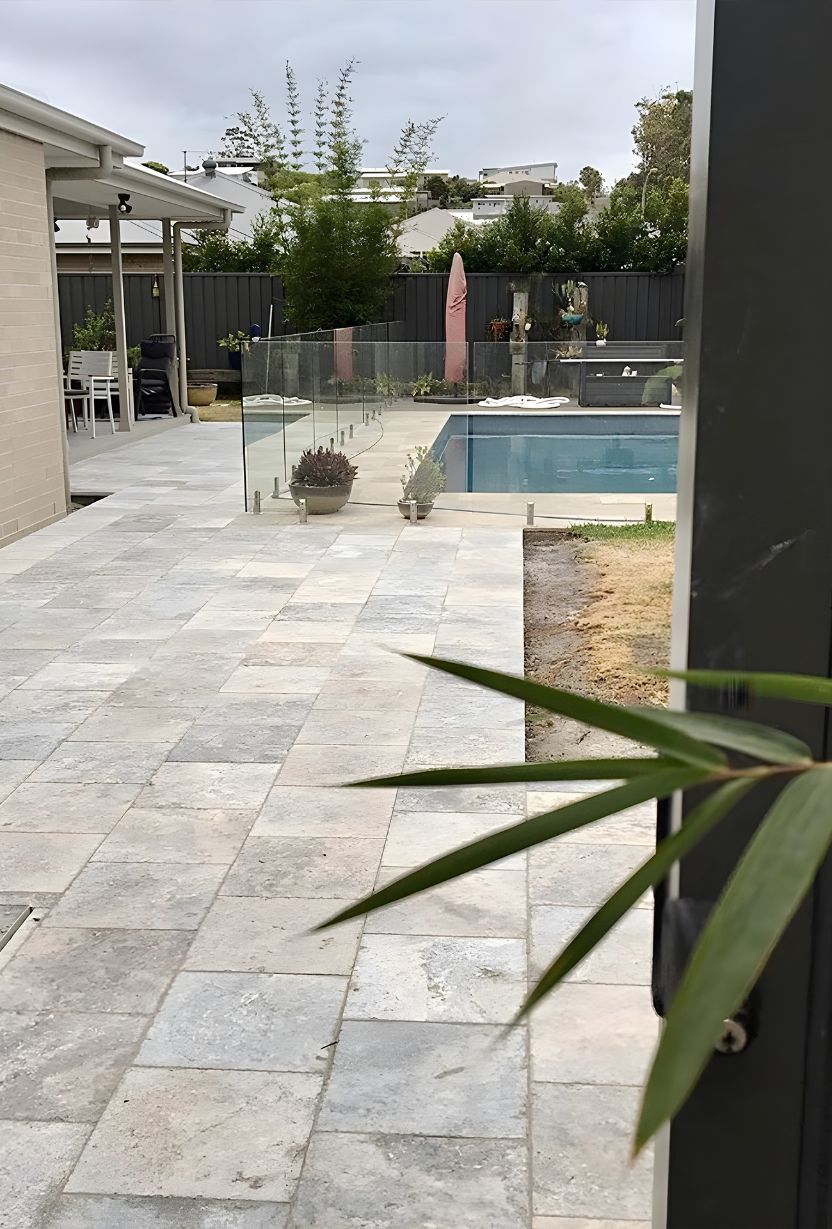 A Patio With A Swimming Pool In The Background And A Palm Tree — Premier Bricks, Blocks & Pavers In Maitland, NSW