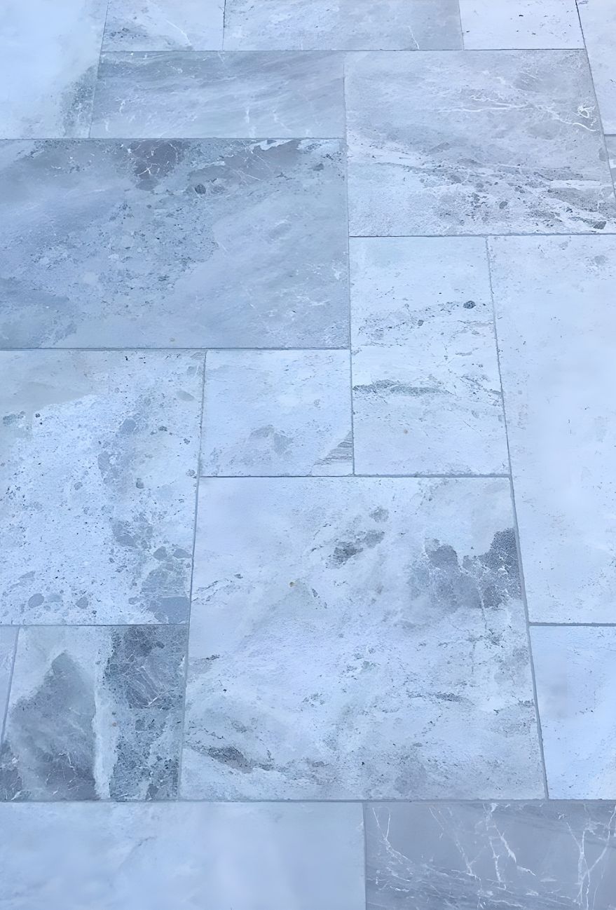 A Close Up Of A Tiled Floor With A Blue Background — Premier Bricks, Blocks & Pavers In Lake Macquarie, NSW