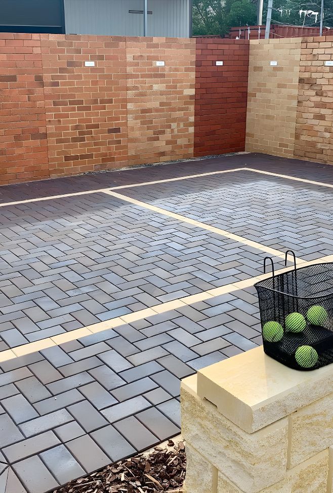 A Basket Of Tennis Balls Sits On A Brick Wall In A Parking Lot — Premier Bricks, Blocks & Pavers In Merewether, NSW