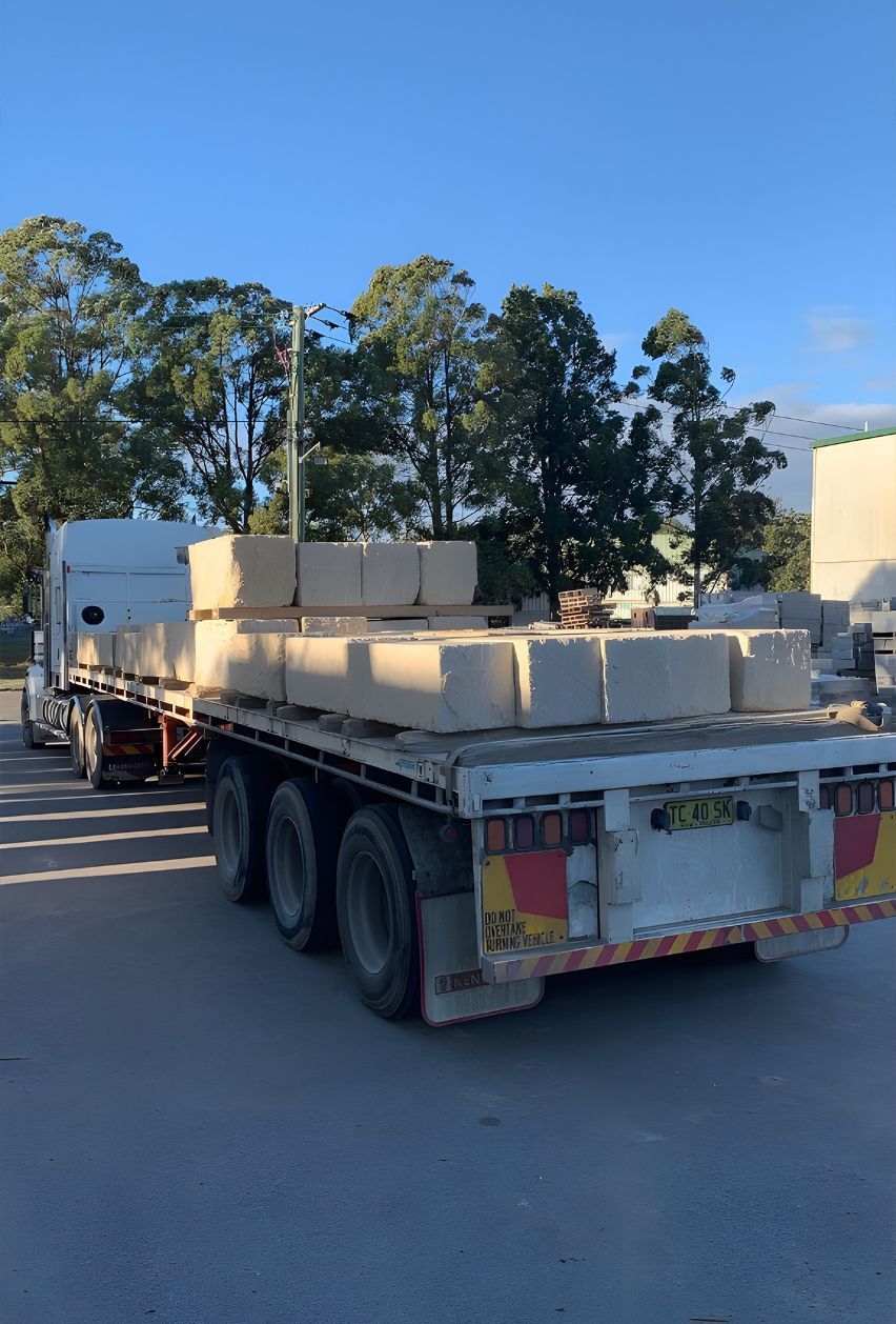 A Truck Is Carrying Bricks On A Flatbed Trailer — Premier Bricks, Blocks & Pavers In Hawks Nest, NSW