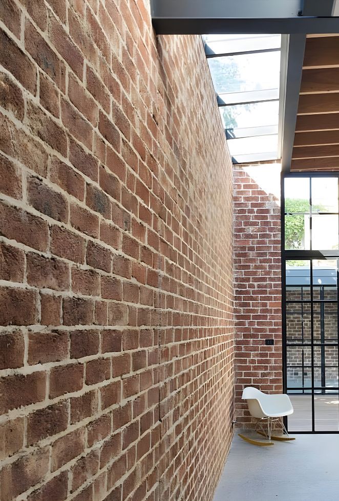 A Long Hallway With A Brick Wall And A Rocking Chair — Premier Bricks, Blocks & Pavers In Port Stephens, NSW