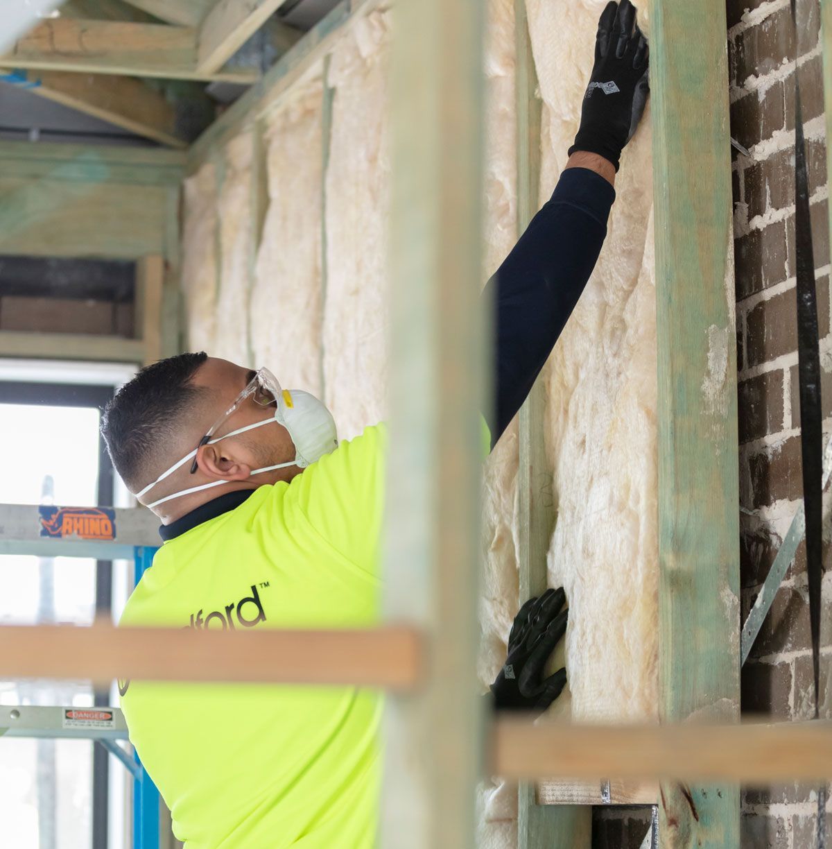 Installer fitting insulation batts into an external wall frame