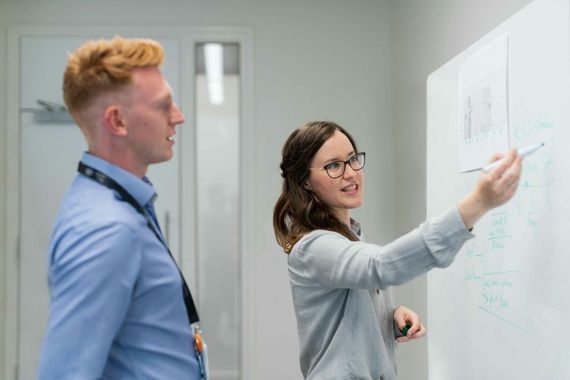 Férfi és női kolléga egy whiteboard előtt tervezi a bértranszparencia projektre felkészülést