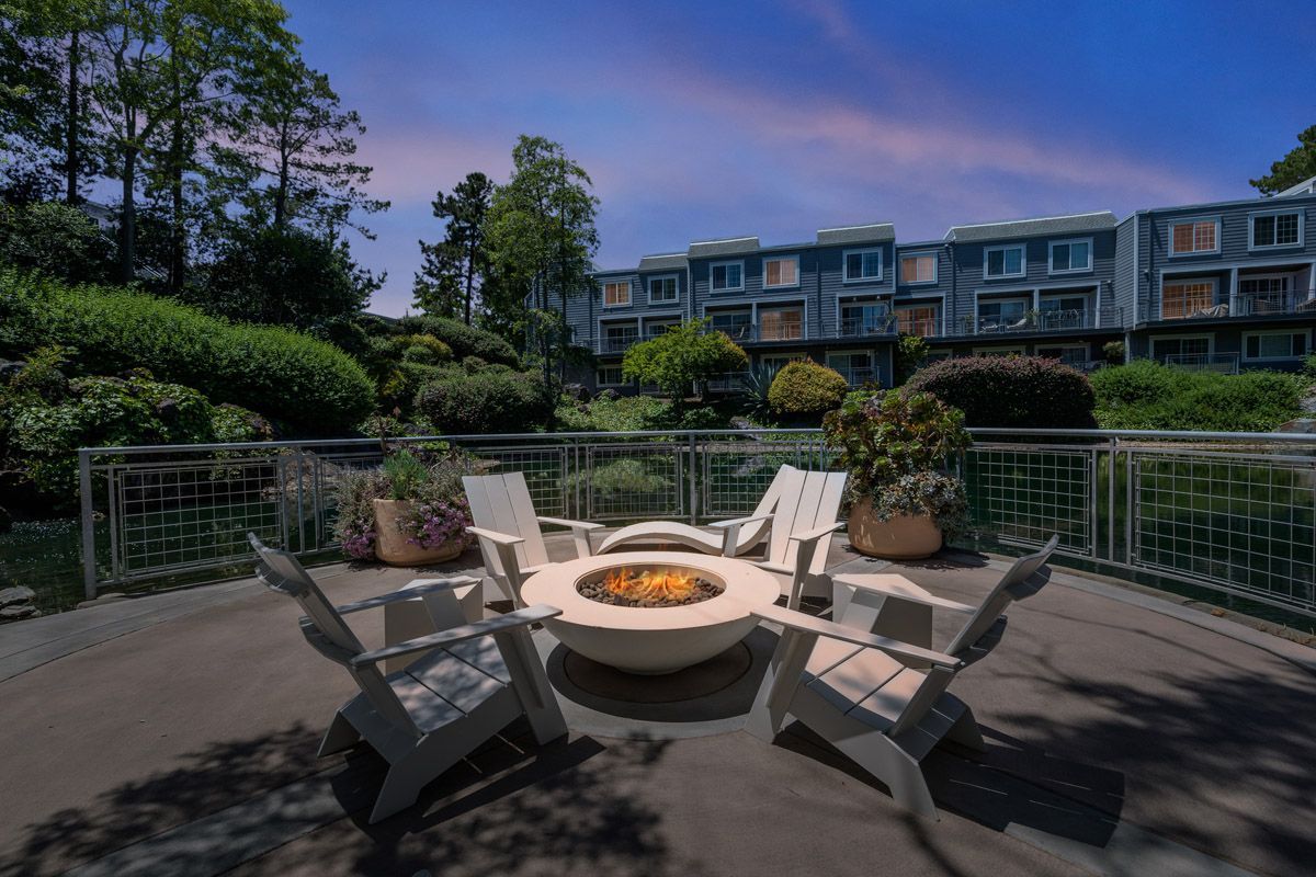Outdoor communal fire pit surrounded by chairs on a deck, with apartment buildings in the background. Explore 1 and 2 bedroom apartments and townhomes in Larkspur, CA with modern floor plans and a convenient location just a 30-minute drive from San Francisco.